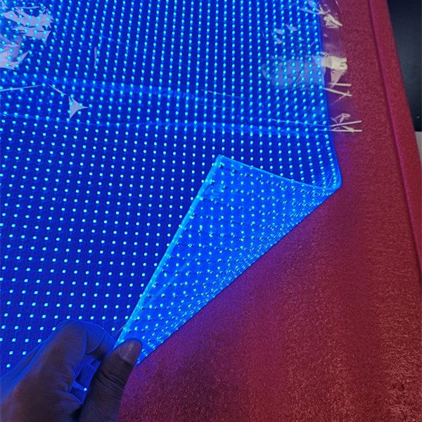 Malla LED transparente sostenida con la mano, mostrando la transparencia real del material cuando no proyecta contenido